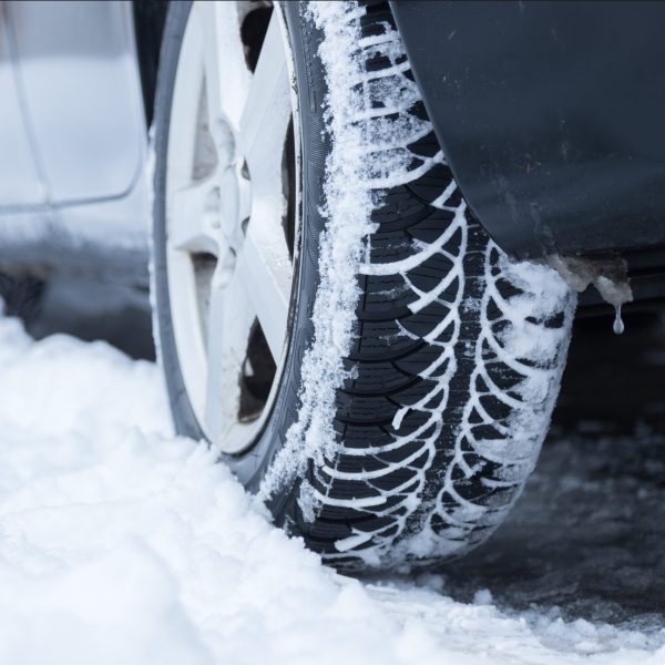Close up of car tire covered with snow on a slippery road